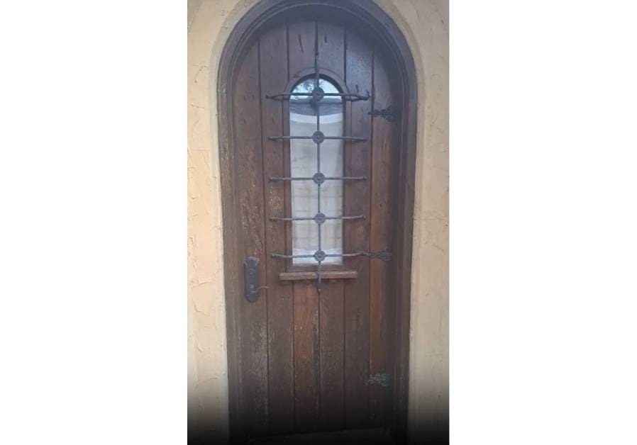 A wooden door with a metal window on the side.