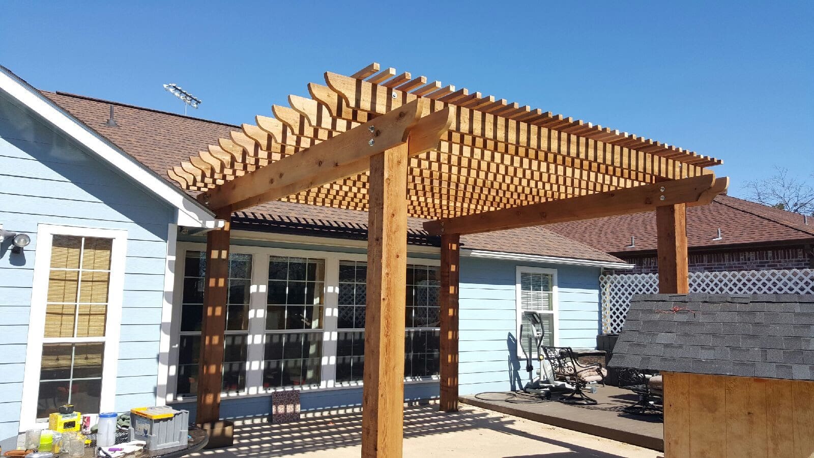 A wooden pergola sitting in the middle of a patio.